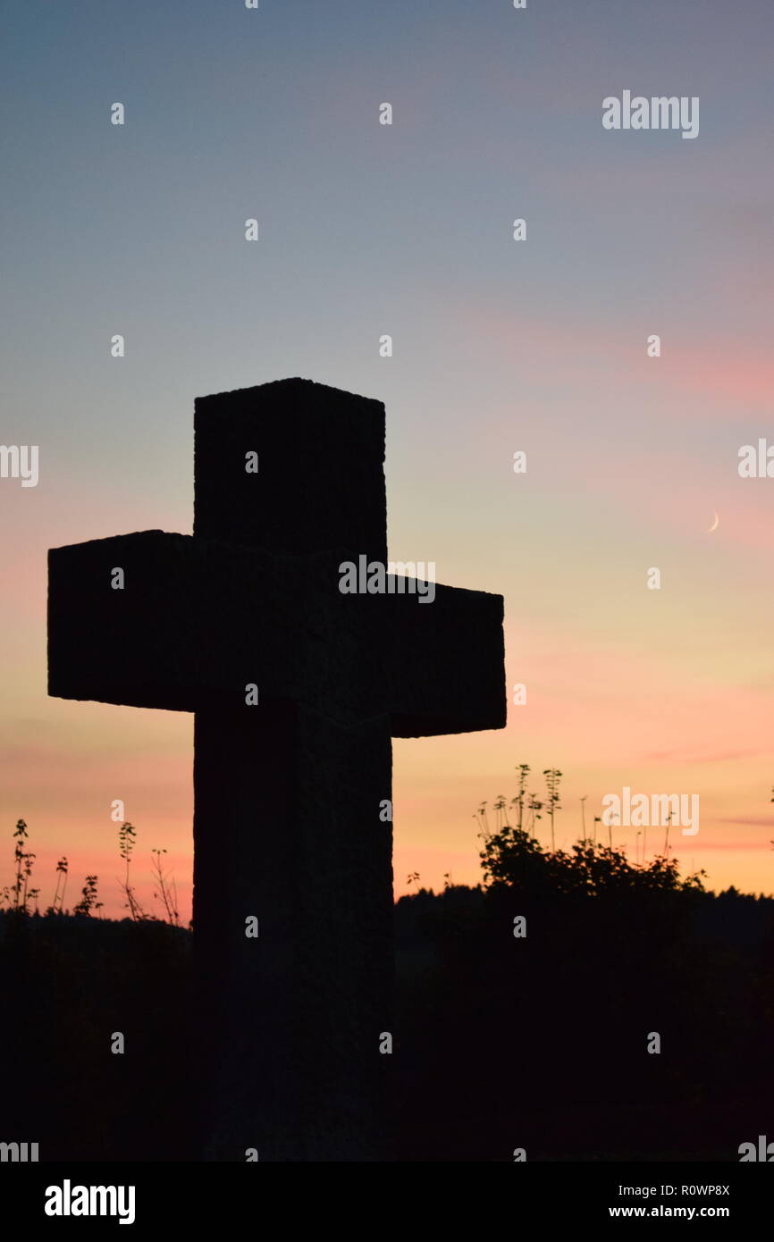 Chronologie de la soirée ciel crépuscule vu de derrière une croix en pierre de sable sculpture au cours de la coucher du soleil soleil dans le cimetière civil Reimsbach, Centre, Banque D'Images