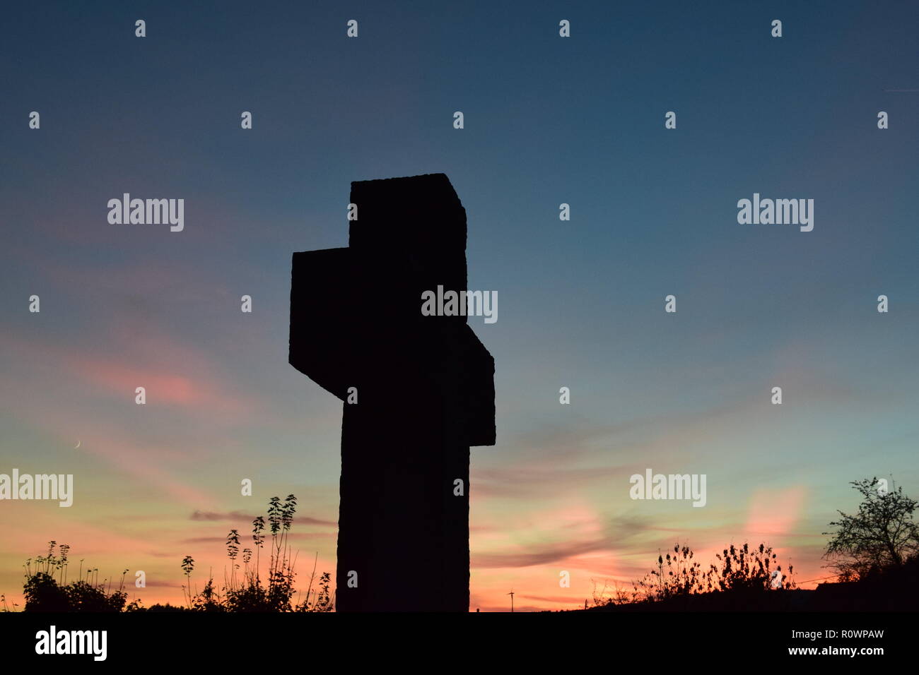 Chronologie de la soirée ciel crépuscule vu de derrière une croix en pierre de sable sculpture au cours de la coucher du soleil soleil dans le cimetière civil Reimsbach, Centre, Banque D'Images