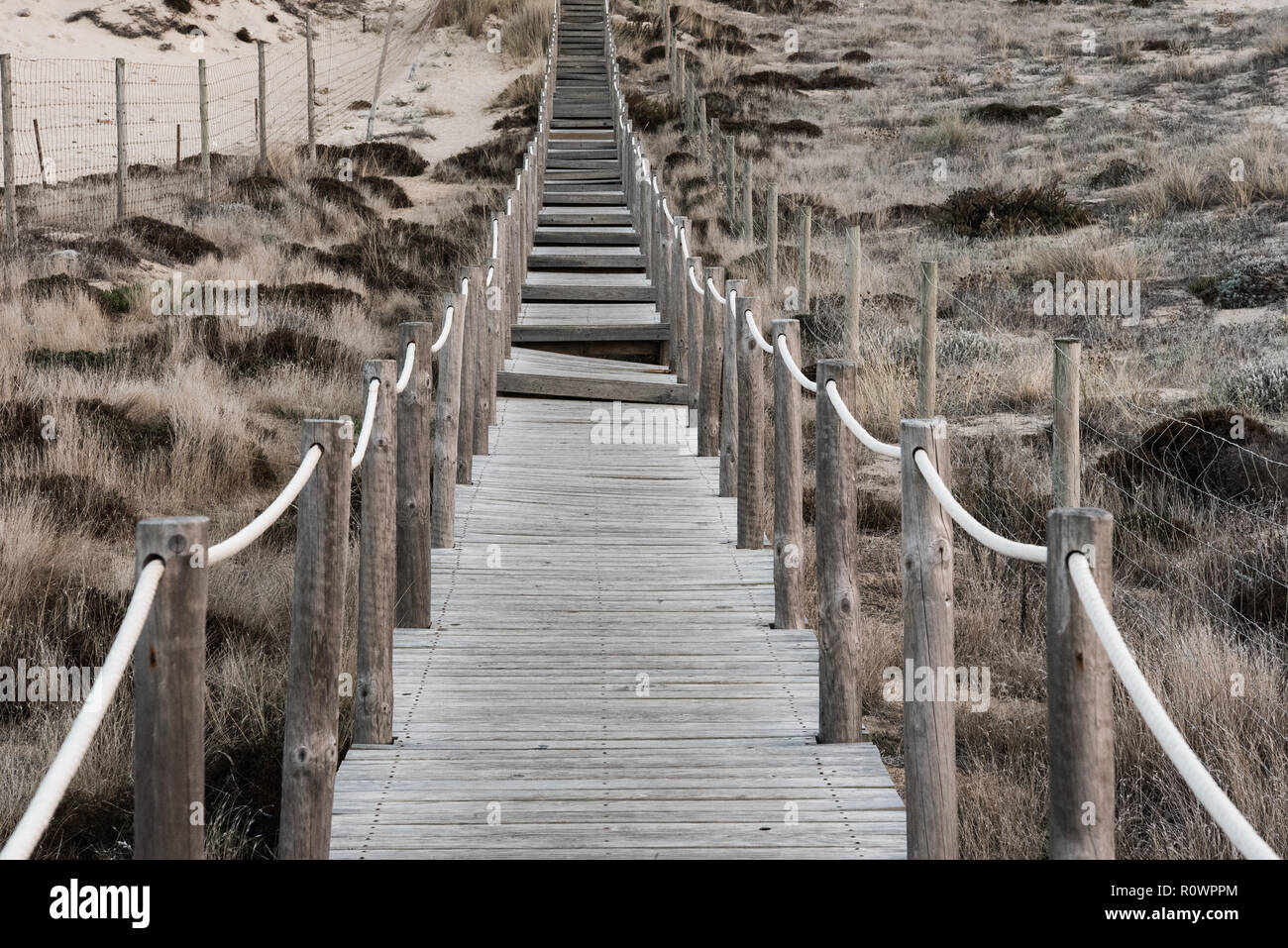 Promenade en bois délabrées et essuyé avec corde rampes menant vers la colline herbacé des dunes de sable. Profondeur de champ long Sharp Banque D'Images