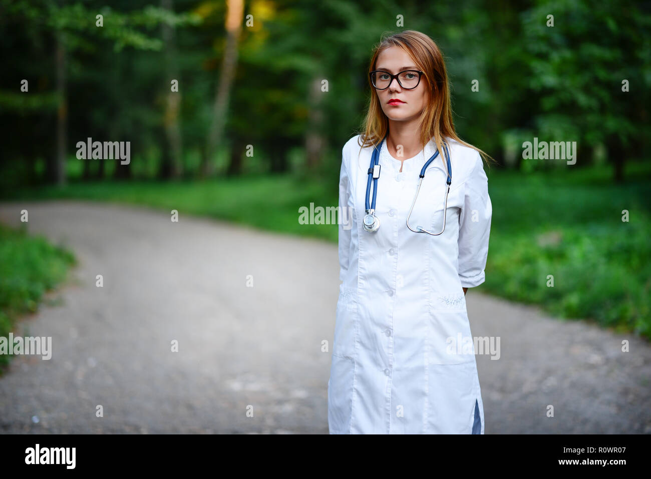 Une jeune fille qui est médecin se trouve à l'extérieur, elle a croisa les bras sur sa poitrine. Banque D'Images