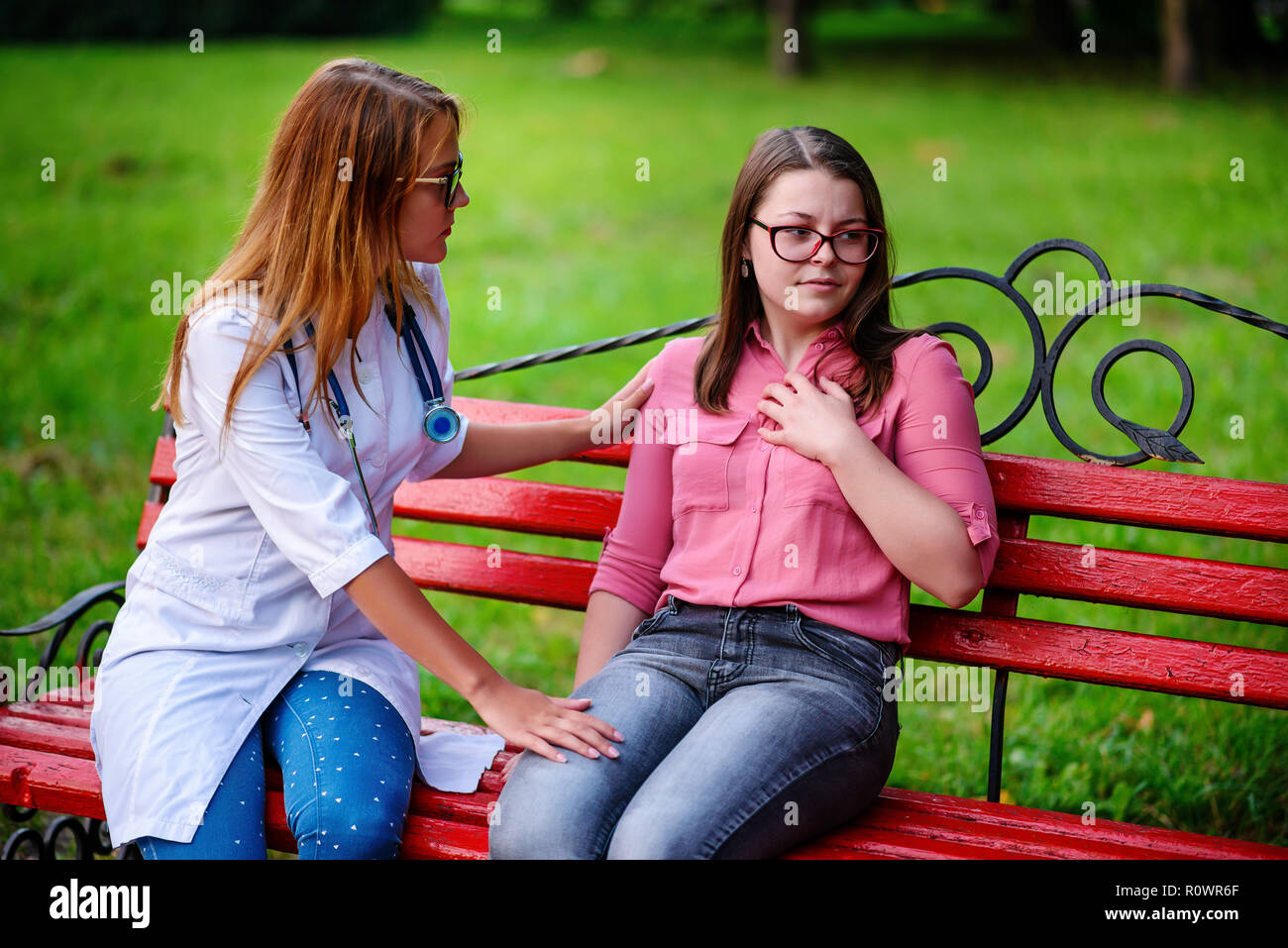 Prendre soin médecin ou infirmière prendre jeune patient à l'extérieur, assis sur un banc, tenir une conversation. Banque D'Images