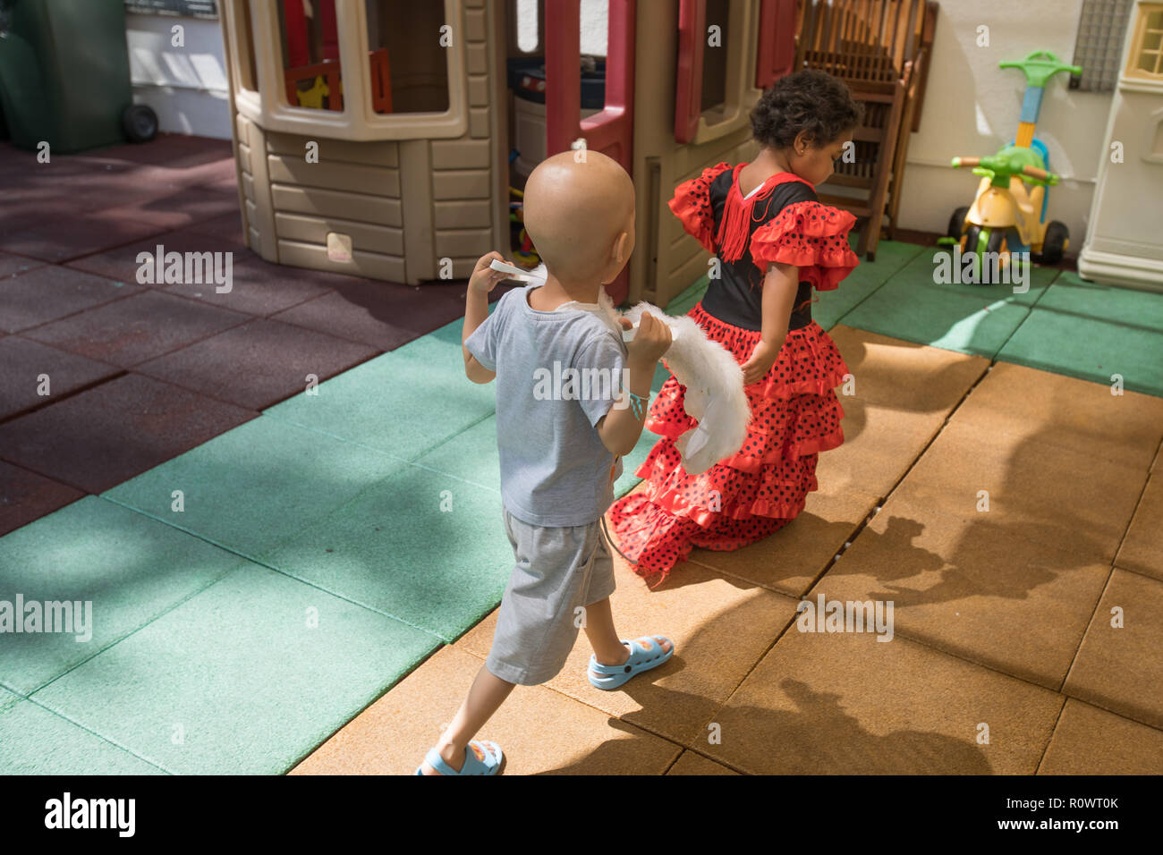 Jeune garçon et fille avec le cancer jouant sur des jeux pour enfants avec toy house sur l'arrière-plan. Banque D'Images