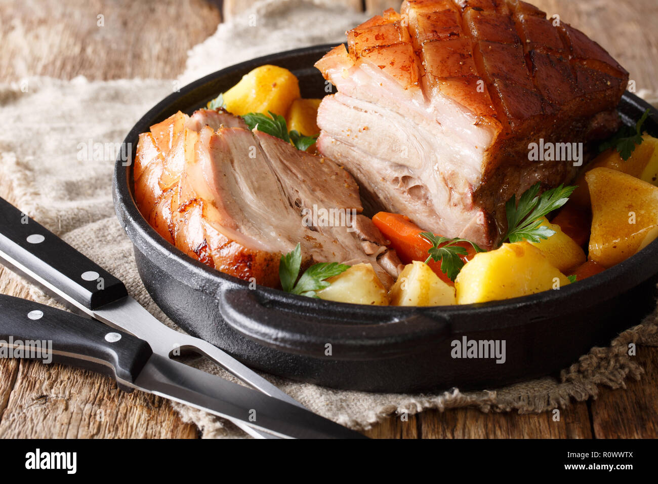 Porc croustillant délicieux cuit dans la bière avec légumes et sauce close-up dans une poêle sur la table horizontale. Banque D'Images