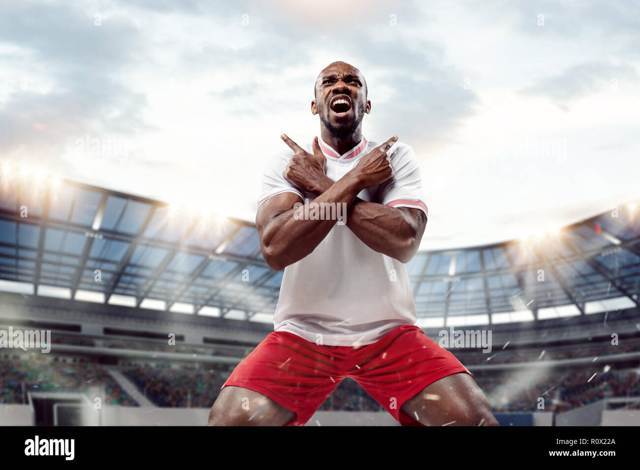 Le joueur africain de football en mouvement sur le terrain de stade à jour. Le football professionnel, joueur de football et émotions humaines concept. Le win, gagnant, concept de la victoire Banque D'Images