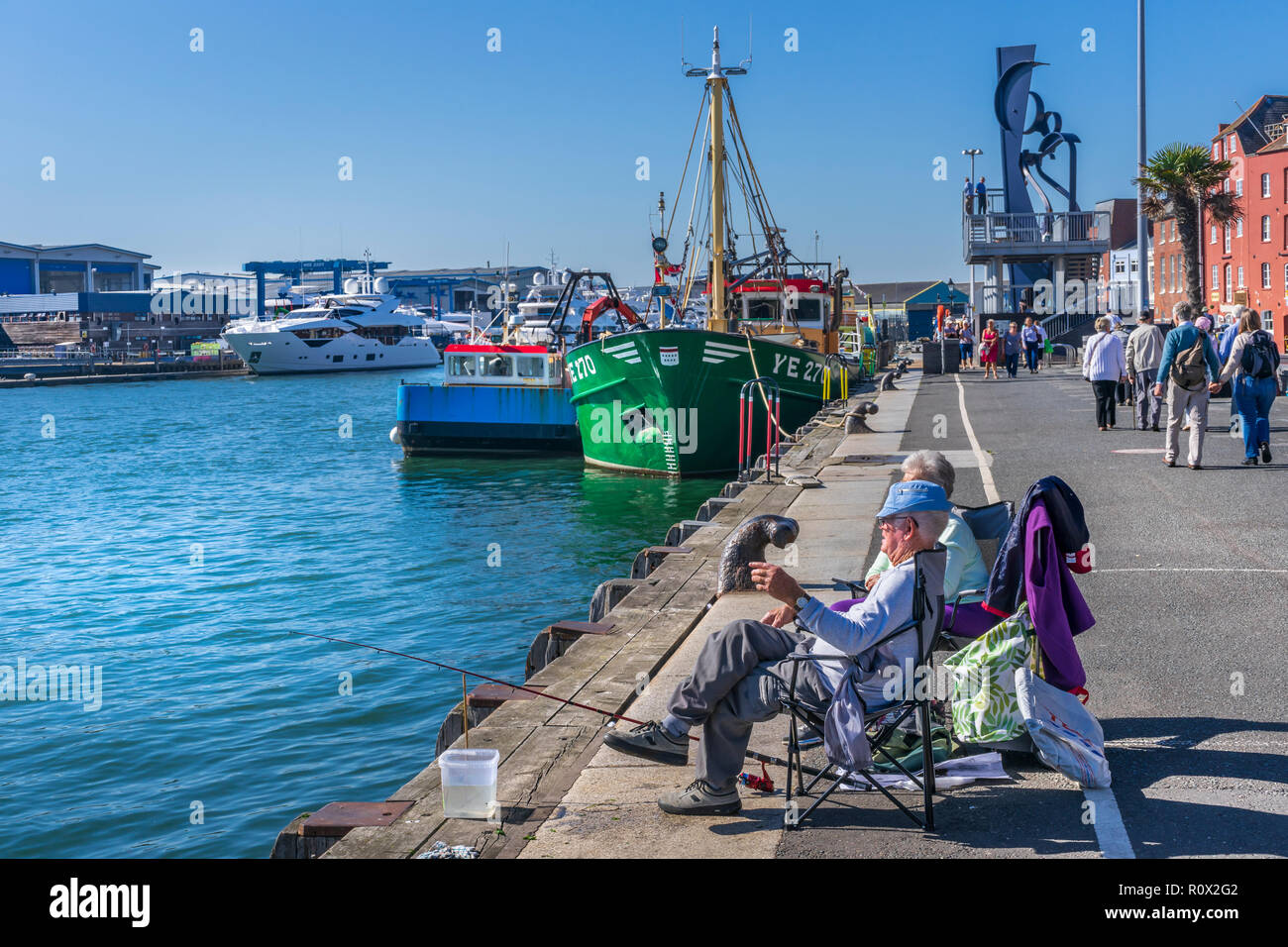 Un couple de personnes âgées jouissent d'un anothers entreprise que ils pêchent sur le quai en face de Sunseeker quai au port de Poole, dans le Dorset. Banque D'Images