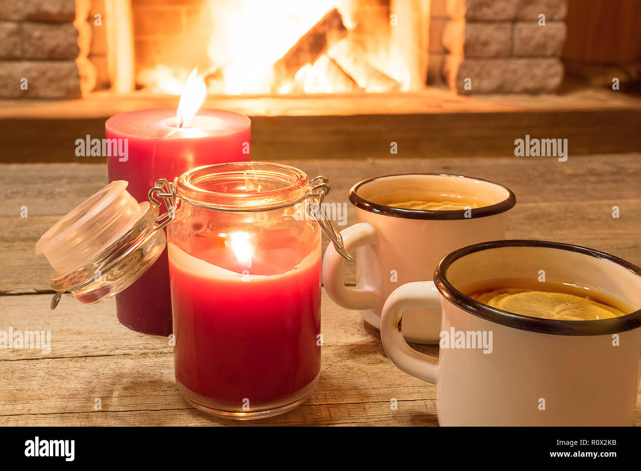 Deux tasses émaillé blanc avec du thé chaud, et des bougies , près de foyer, en maison de vacances d'hiver, à l'horizontale. Banque D'Images