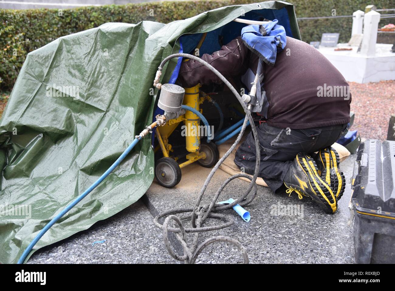 Gravure sur pierre tombale : un enterrement mason sablé une nouvelle inscription sur une pierre tombale dans un cimetière français rural sous la pluie Banque D'Images