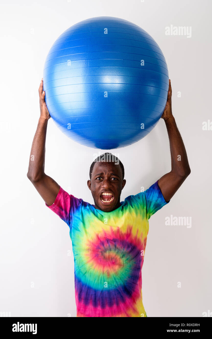 Studio shot of young black African man holding big boule d'exercice Banque D'Images