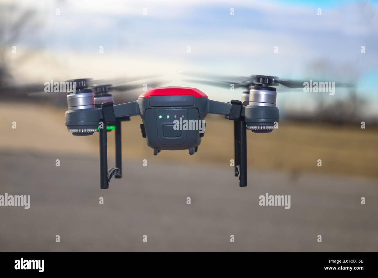 Petit rouge et gris drone avec joint d'atterrissage et batterie à demi-charge battant contre l'arrière-plan flou Banque D'Images