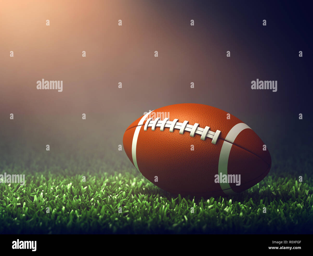 Ballon de football américain sur l'herbe allumé par spotlight, arène sportive Banque D'Images