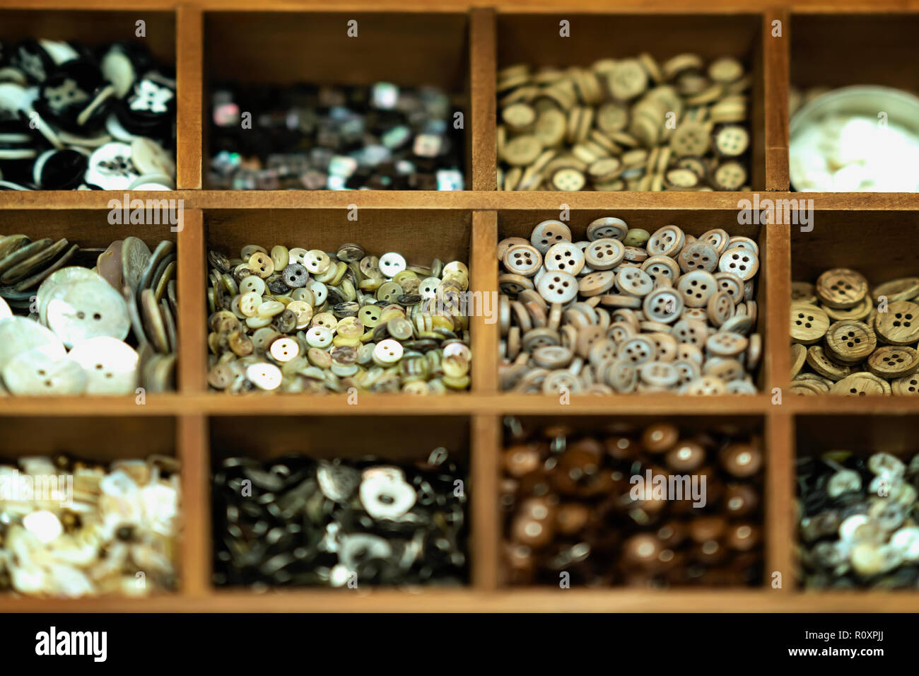 Différents boutons multicolores dans des caisses en bois pour la créativité, un vrai magasin, arrière-plan sélectif. L'industrie textile, l'habillement, les loisirs, fait main Banque D'Images