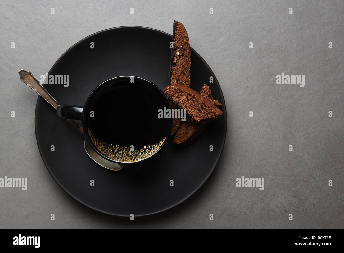 High angle shot de biscotti au chocolat et tasse à café et soucoupe sur un tableau gris ardoise. Banque D'Images