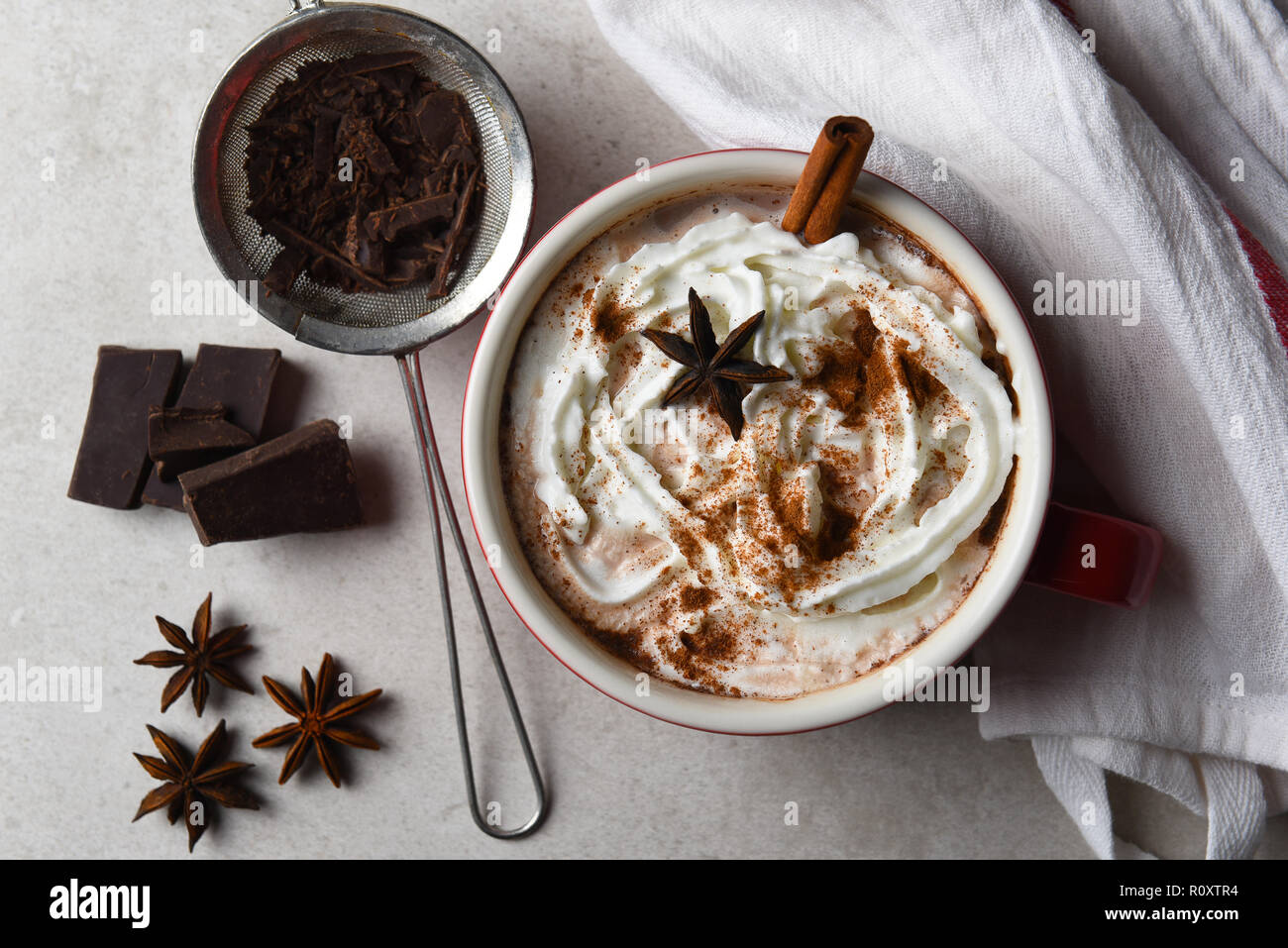 Vue de dessus d'une grande tasse de chocolat chaud recouvert de crème fouettée et de cannelle et anis étoilé. Banque D'Images