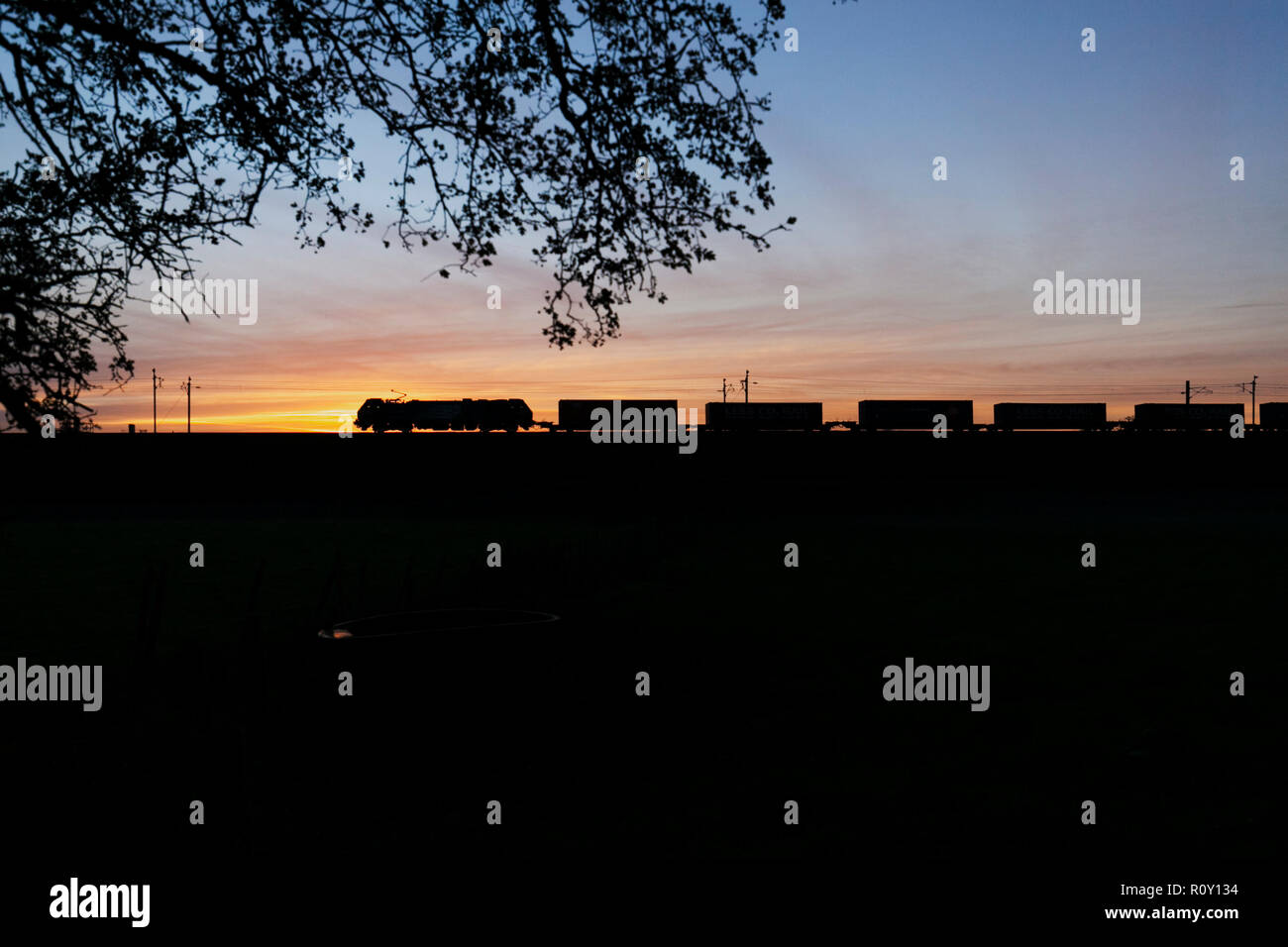 Services ferroviaires directs 88 locomotive sur la ligne principale de la côte ouest au coucher du soleil avec le Stobart / Tesco moins de CO2 du train de conteneurs intermodaux Banque D'Images