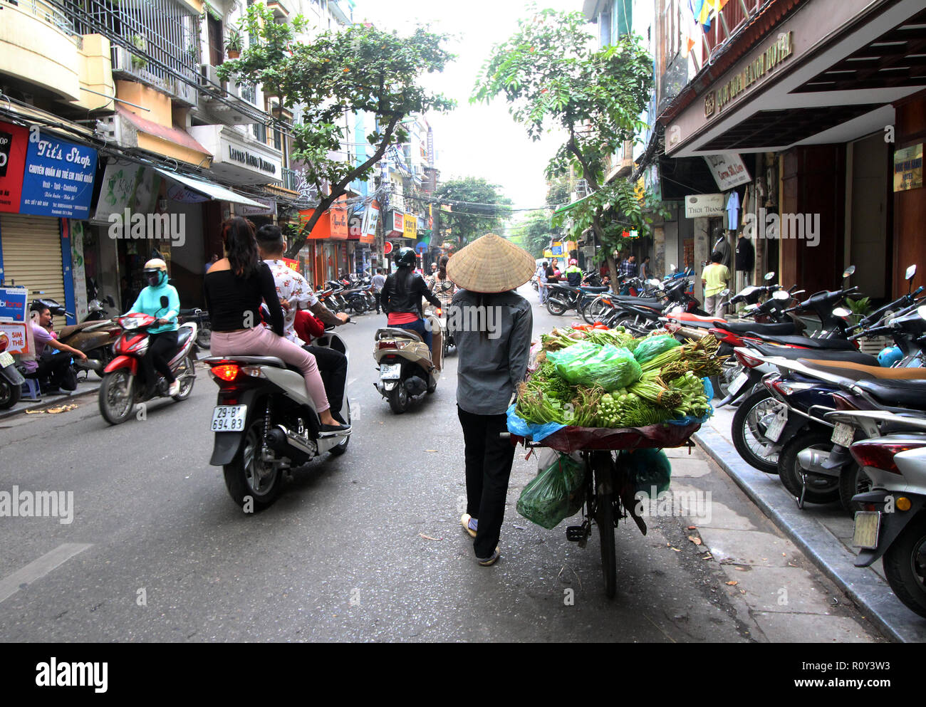 Les femmes produisent des biens du vendeur son se déplace dans les rues en vélo, Hanoi, Vietnam Banque D'Images