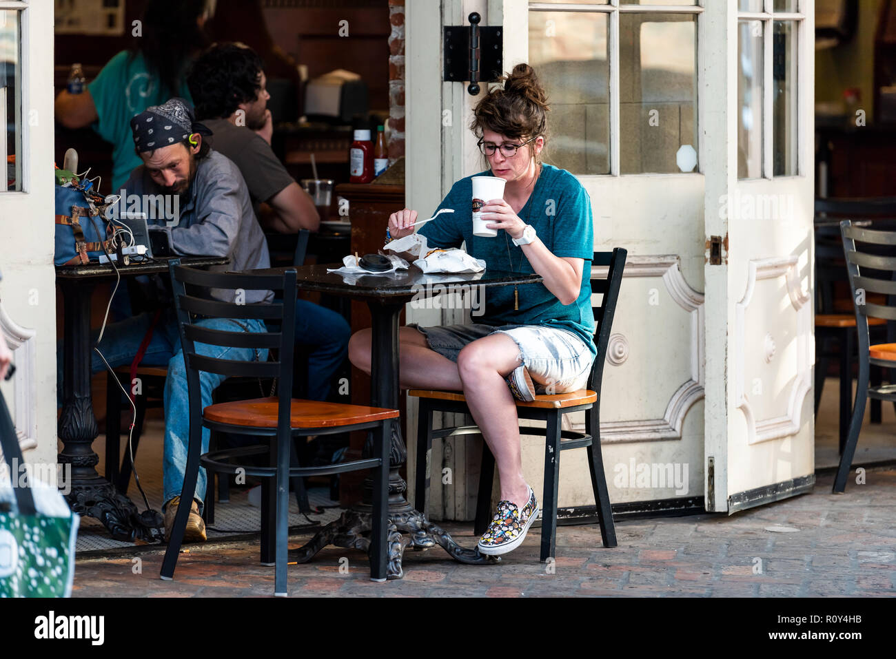 New Orleans, USA - 22 Avril 2018 : dans la région de Decatur Street Louisiane célèbre ville, ville, en soirée, woman drinking coffee at cafe envie, s'asseoir en piscine Banque D'Images