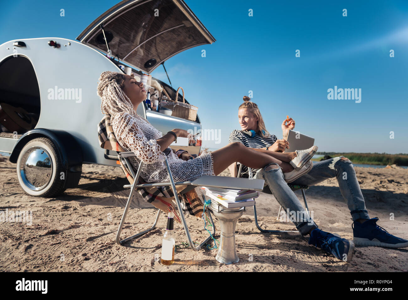 Femme avec des dreadlocks cigarette mettant ses jambes sur l'ami Banque D'Images