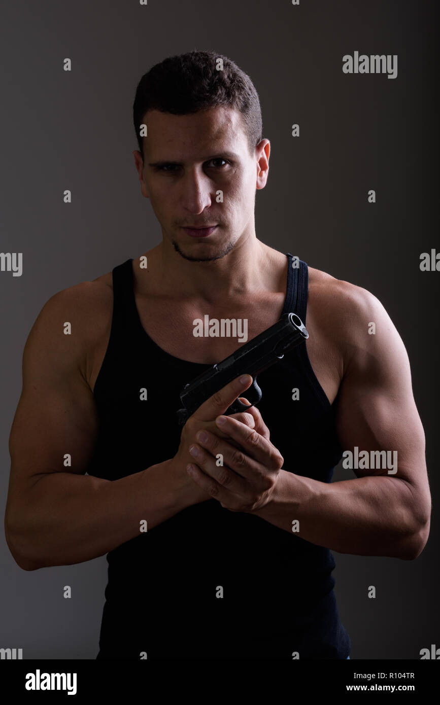 Portrait of young man holding gun persan musculaire et lookin Banque D'Images