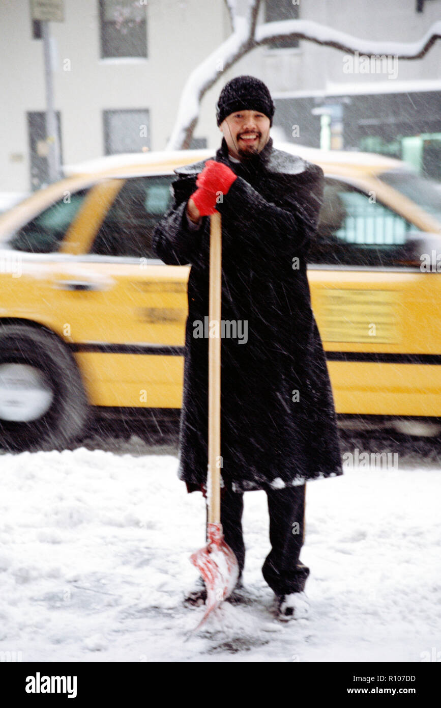 Appartement Maison portier pelleter la neige sur le trottoir, NYC, USA Banque D'Images