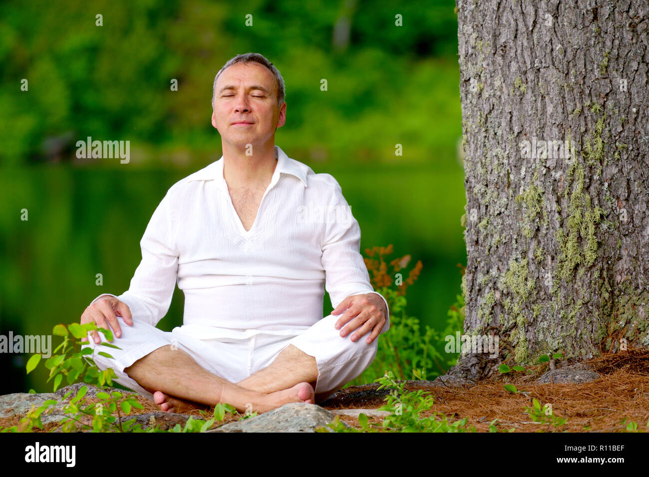 Portrait d'une saine fierté caucasian man, 50 ans, vêtu d'un costume blanc, après une session de méditation par la rivière au coucher du soleil. Banque D'Images