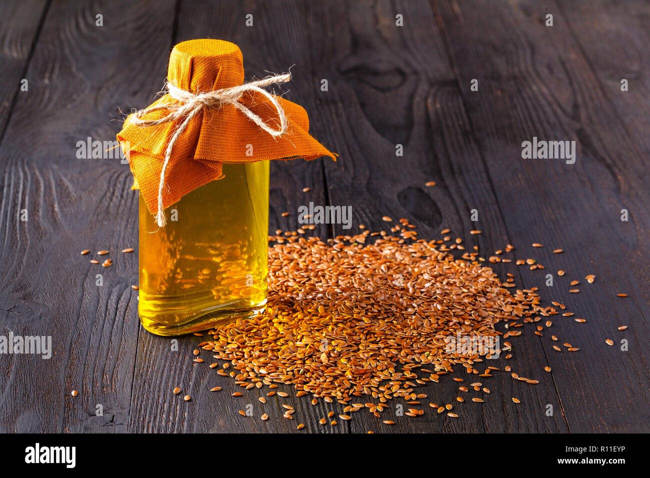 Graines de lin brun et une cuillère dans l'huile de lin dans le flacon en verre blanc sur fond de bois. L'huile de lin est riche en acide gras oméga-3 Banque D'Images