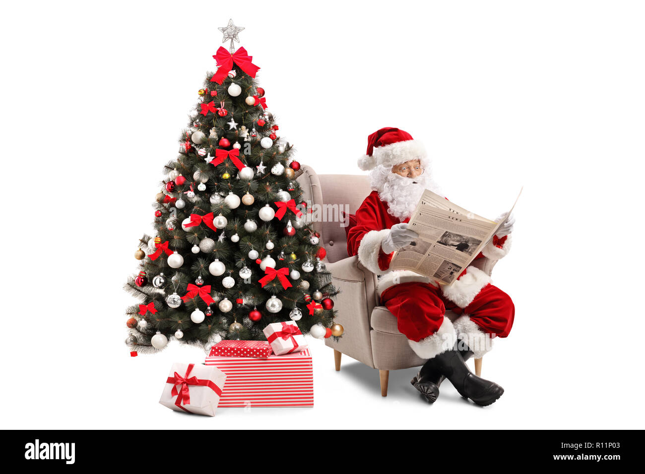 Surpris le Père Noël assis dans un fauteuil et lit un journal isolé sur fond blanc Banque D'Images