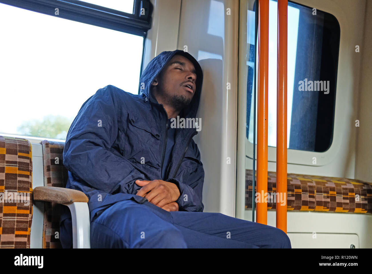 Un homme noir endormi sur un train de tube Banque D'Images