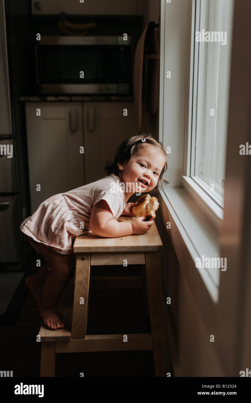 Girl leaning on ladder par fenêtre Banque D'Images