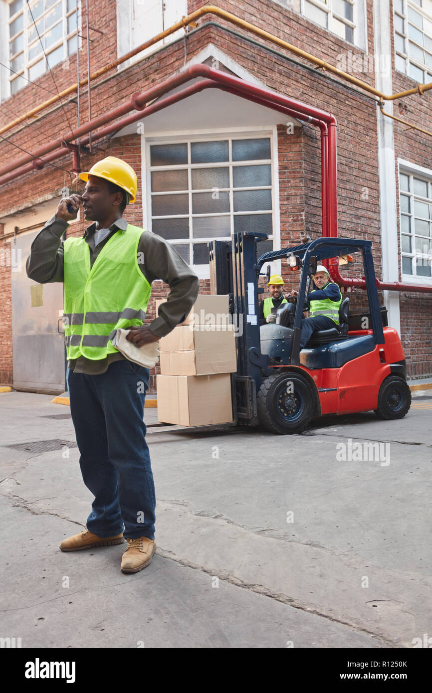 Travailleur avec chariot élévateur et du fret en face de l'entrepôt d'une société de logistique Banque D'Images