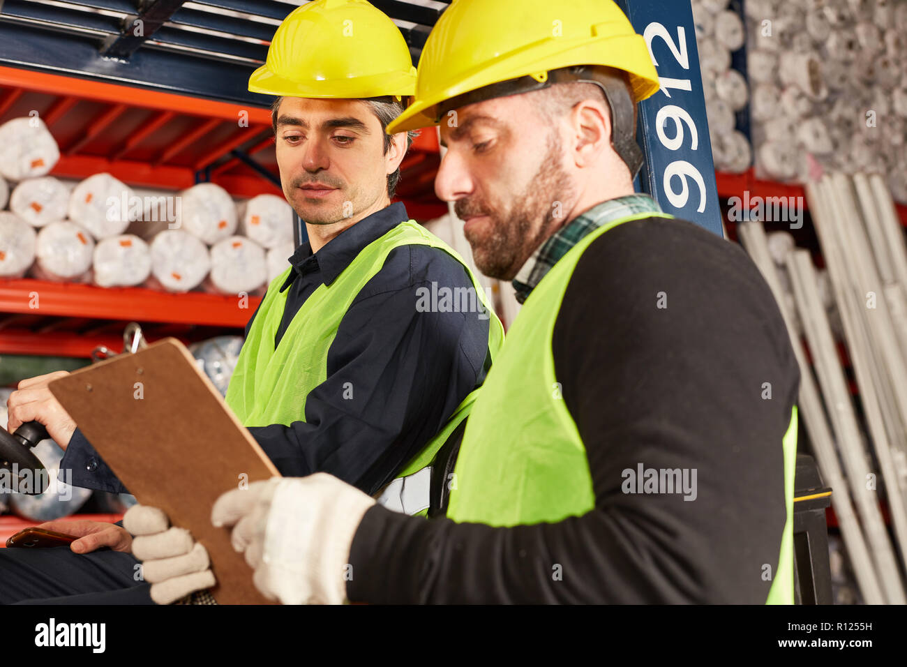 Deux travailleurs de la logistique avec presse-papiers prendre des marchandises dans l'entrepôt pour l'expédition Banque D'Images