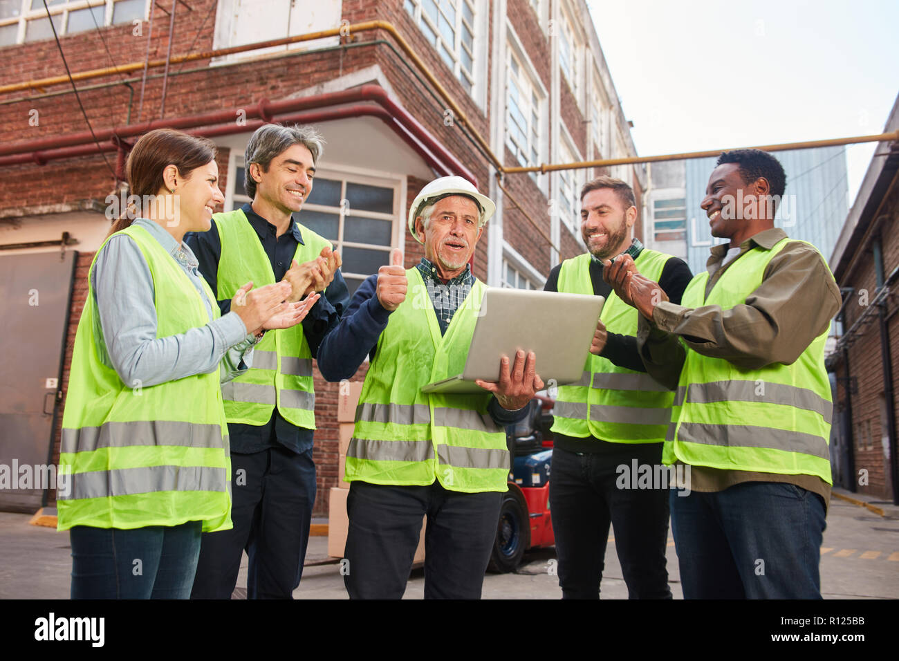 L'équipe logistique réussie avec un ordinateur portable, devant une salle de l'usine Banque D'Images