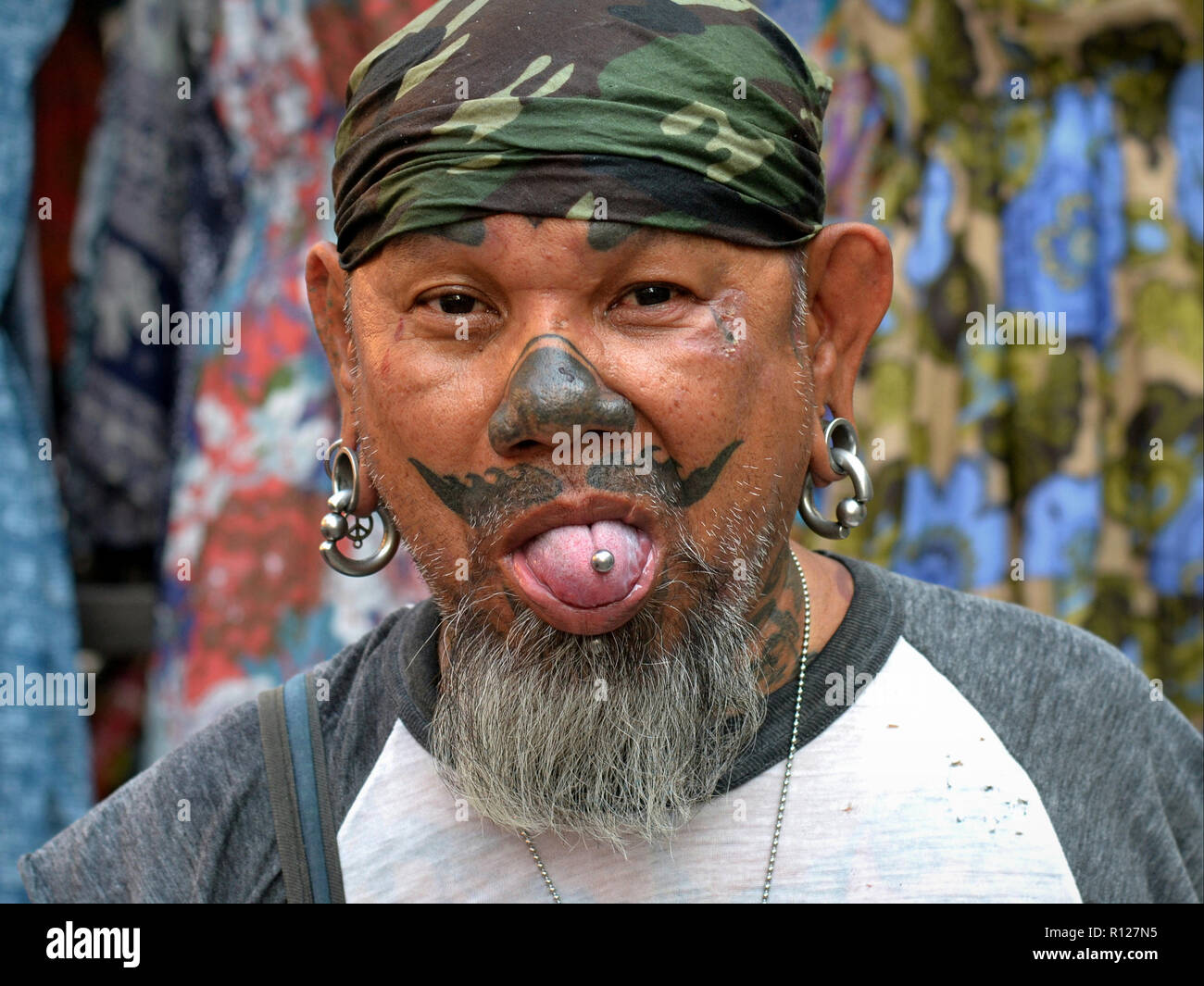 Thai man avec des tatouages faciaux et intéressants et l'oreille piercings langue. Banque D'Images