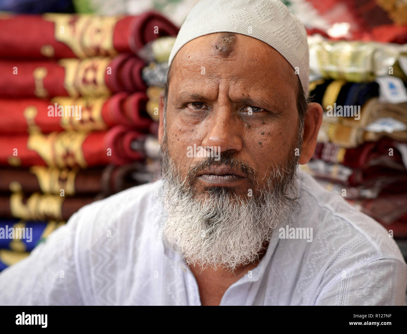 Personnes âgées musulmans indiens marchand avec barbe blanche et islamique très caractéristiques (zebibah) prière bosse sur son front se penche sur l'appareil photo. Banque D'Images