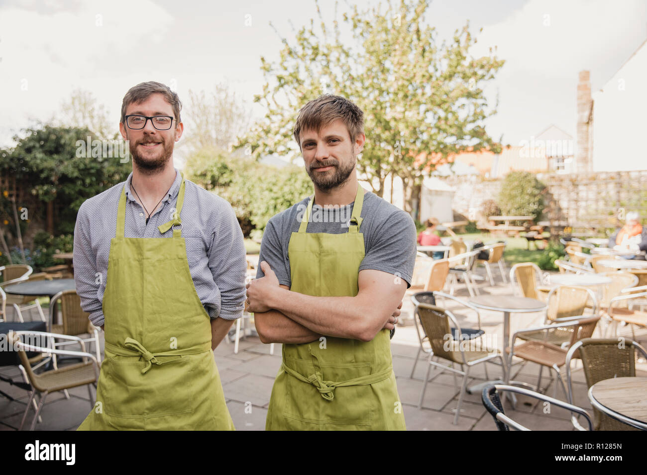 Portrait de deux fiers propriétaires de café debout en face de l'extérieur, coin salon dans leur petit café. Banque D'Images