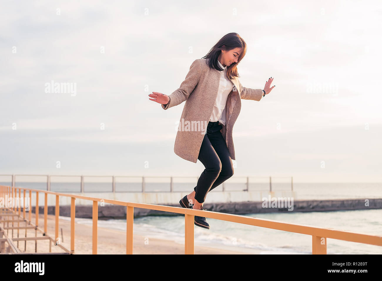 Femme sautant hors de la main courante sur beach Banque D'Images