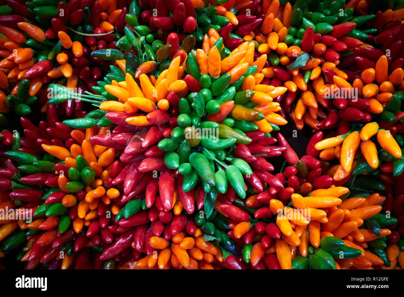 Bouquets de vert, rouge et orange pour les piments dans un marché de vente Banque D'Images