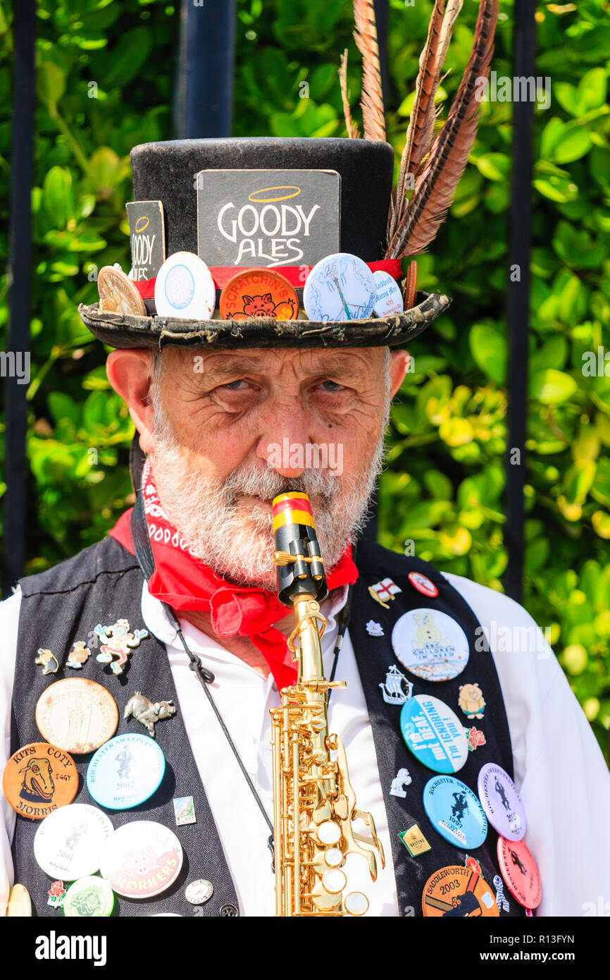 Braodstairs la semaine folklorique. Morris homme musicien face viewer, avec le contact visuel, à jouer du saxophone. Costume noir décorée de nombreux cas de badges. Banque D'Images