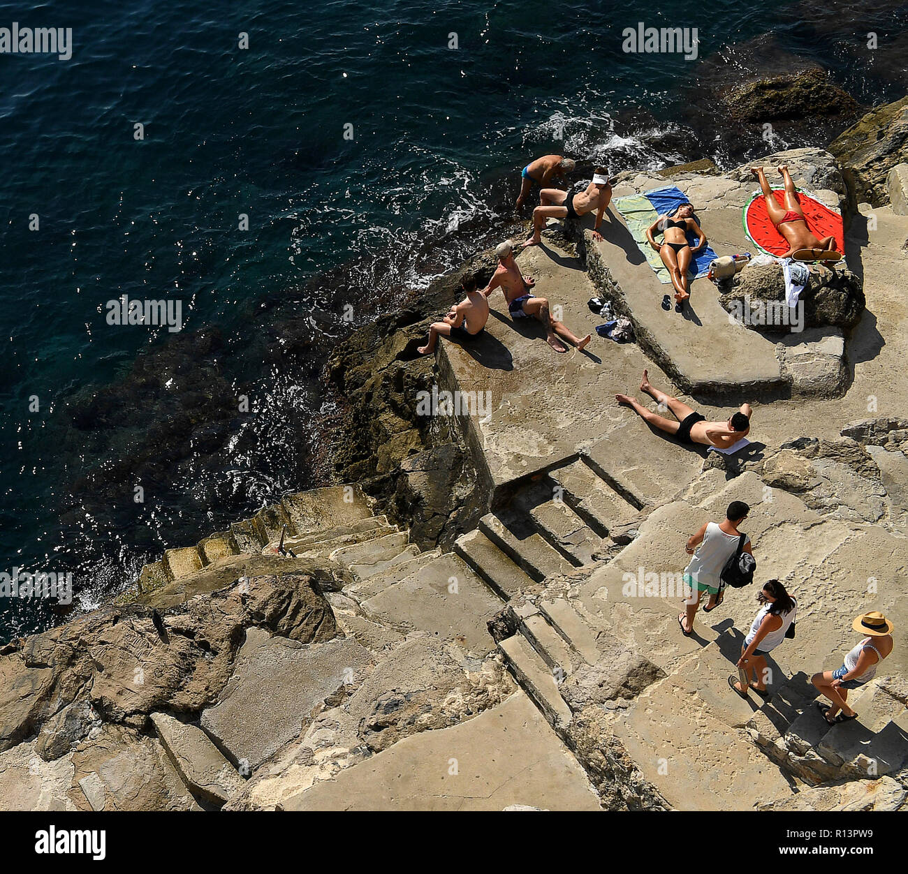 La vieille ville de Dubrovnik les touristes à bronzer sur les rochers sous les murs de la vieille ville Banque D'Images