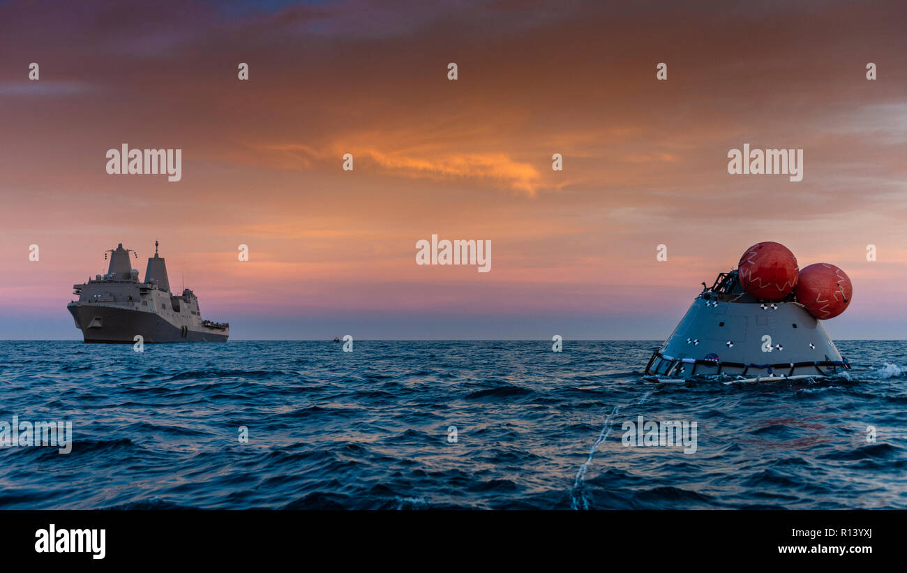 La Marine américaine de transport amphibie USS dock John P. Murtha attend près d'une maquette version de la prochaine génération d'Orion de la NASA capsule spatiale au cours d'un test de récupération au coucher du soleil le 1 novembre 2018 dans l'océan Pacifique. La NASA et la marine américaine n'a pas effectué l'océan ouvert récupération d'un vaisseau spatial habité depuis le projet Apollo dans les années 60 et sont des procédures d'essai et le matériel qui sera utilisé pour récupérer le vaisseau Orion après il éclaboussures vers le bas dans l'océan Pacifique à la suite des futures missions d'exploration spatiale. Banque D'Images