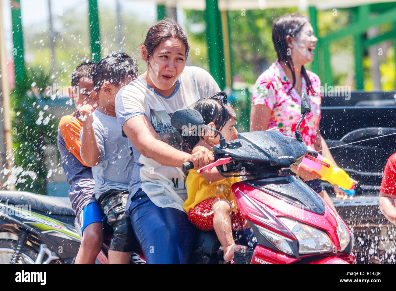 Phuket, Thaïlande - 13 Avril 2018 : Femme avec 3 enfants sur une moto d'être aspergé d'eau. Songkran est la fête du nouvel an Thaï. Banque D'Images