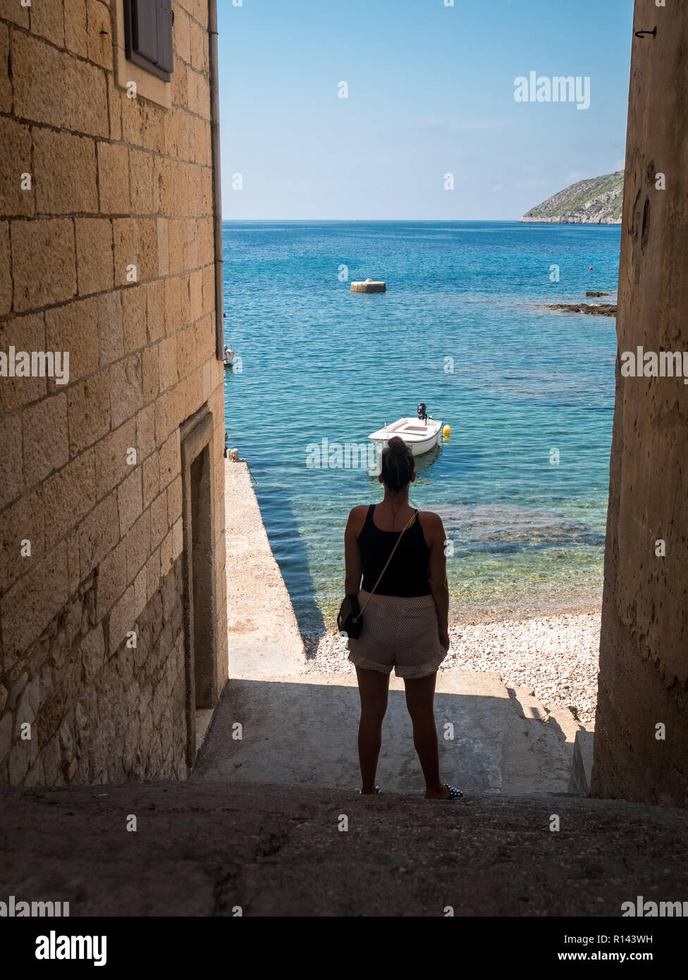 Jeune femme debout sur un escalier en pierre et à la recherche en mer sur l'île de Vis en Croatie Banque D'Images