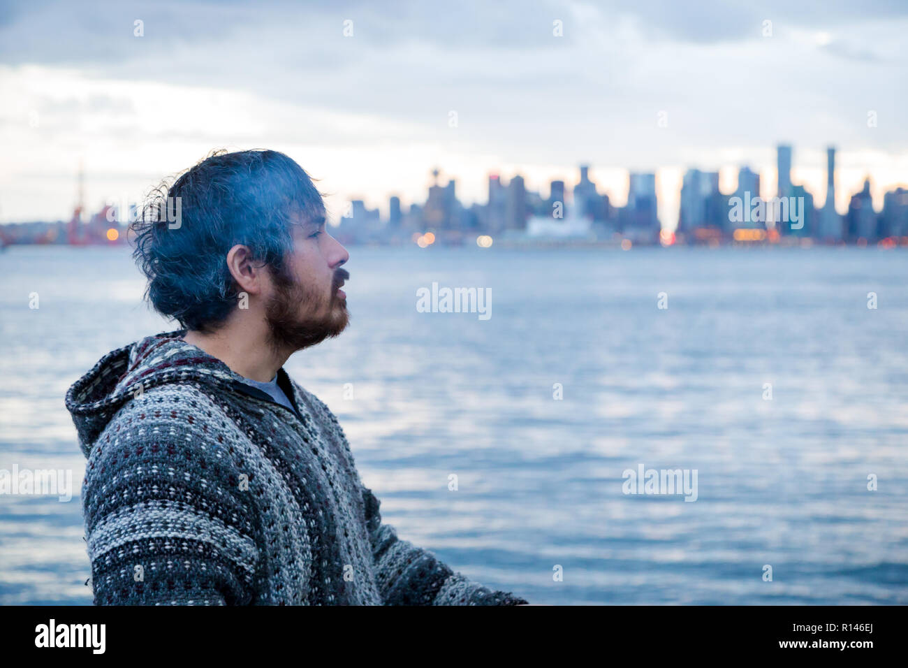 Un jeune homme fumer un joint avec le centre-ville de Vancouver, C.-B., dans l'arrière-plan peu après la légalisation de la marijuana au Canada. Banque D'Images