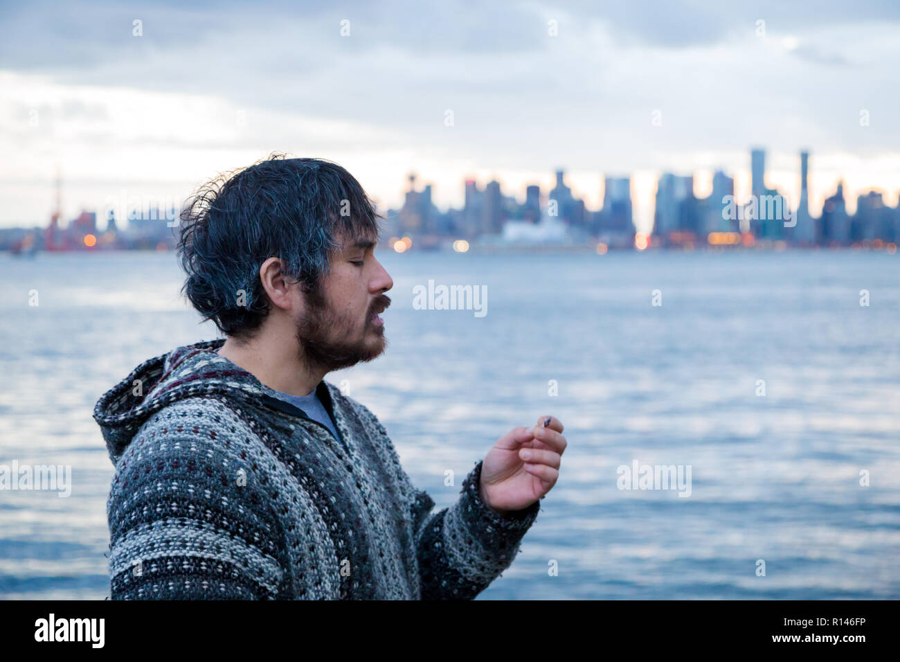 Un jeune homme fumer un joint avec le centre-ville de Vancouver, C.-B., dans l'arrière-plan peu après la légalisation de la marijuana au Canada. Banque D'Images