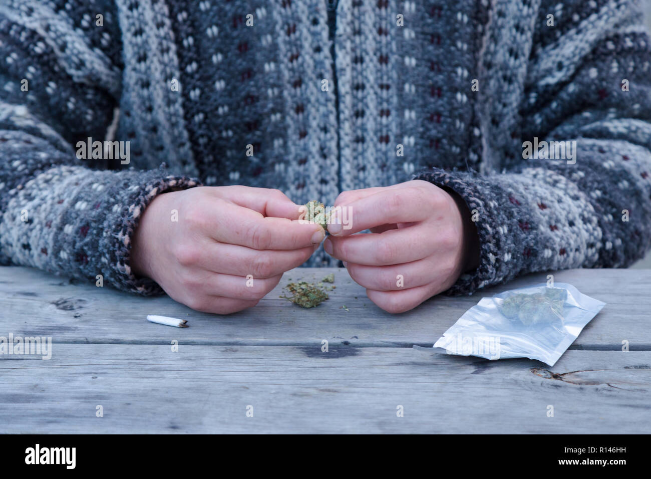 Close-up of a mans mains briser les bourgeons de marijuana à côté d'un dispensaire et un sac de joint. Banque D'Images