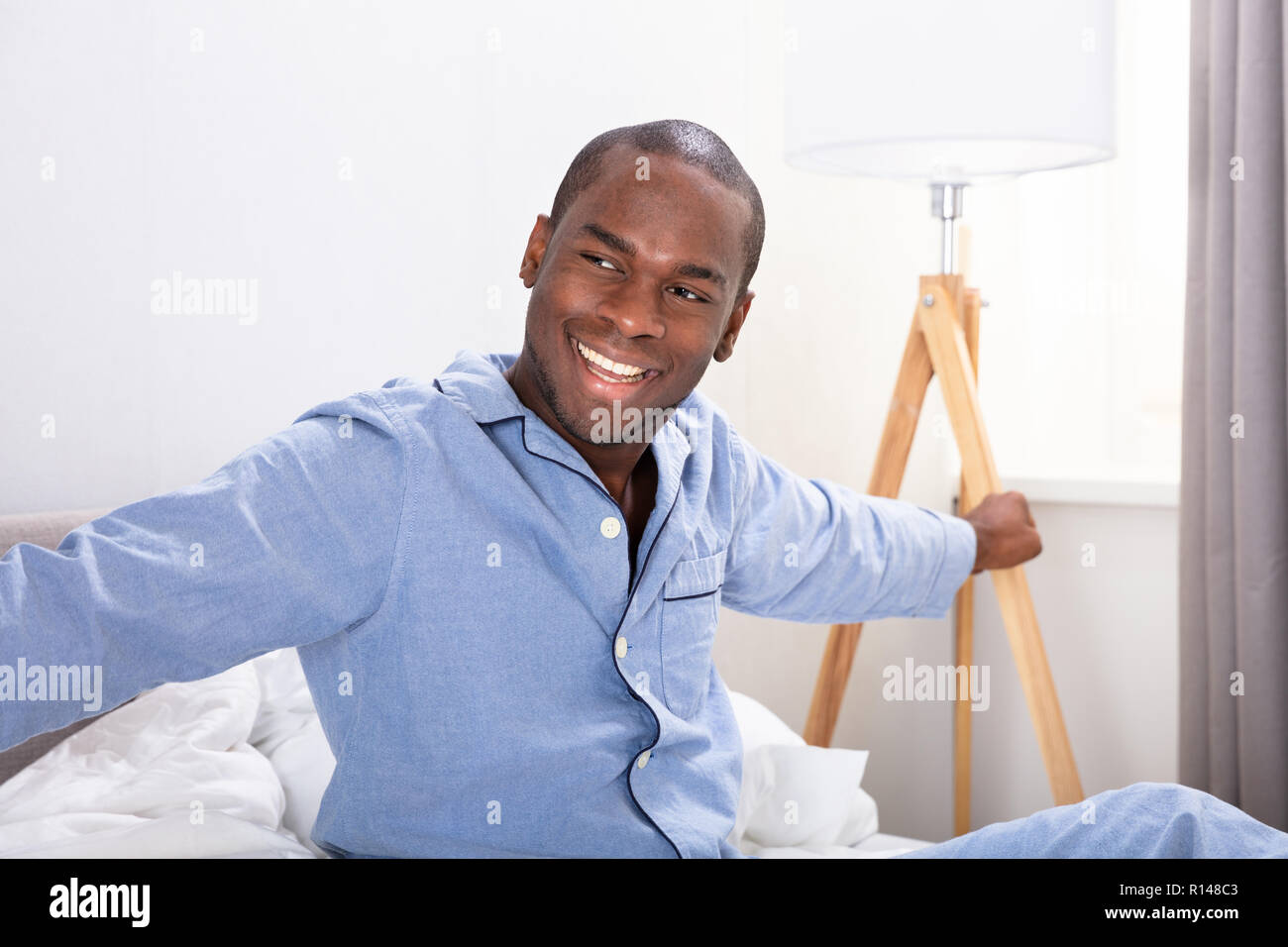 Portrait Of A Happy Young African Man Sitting on Bed Banque D'Images