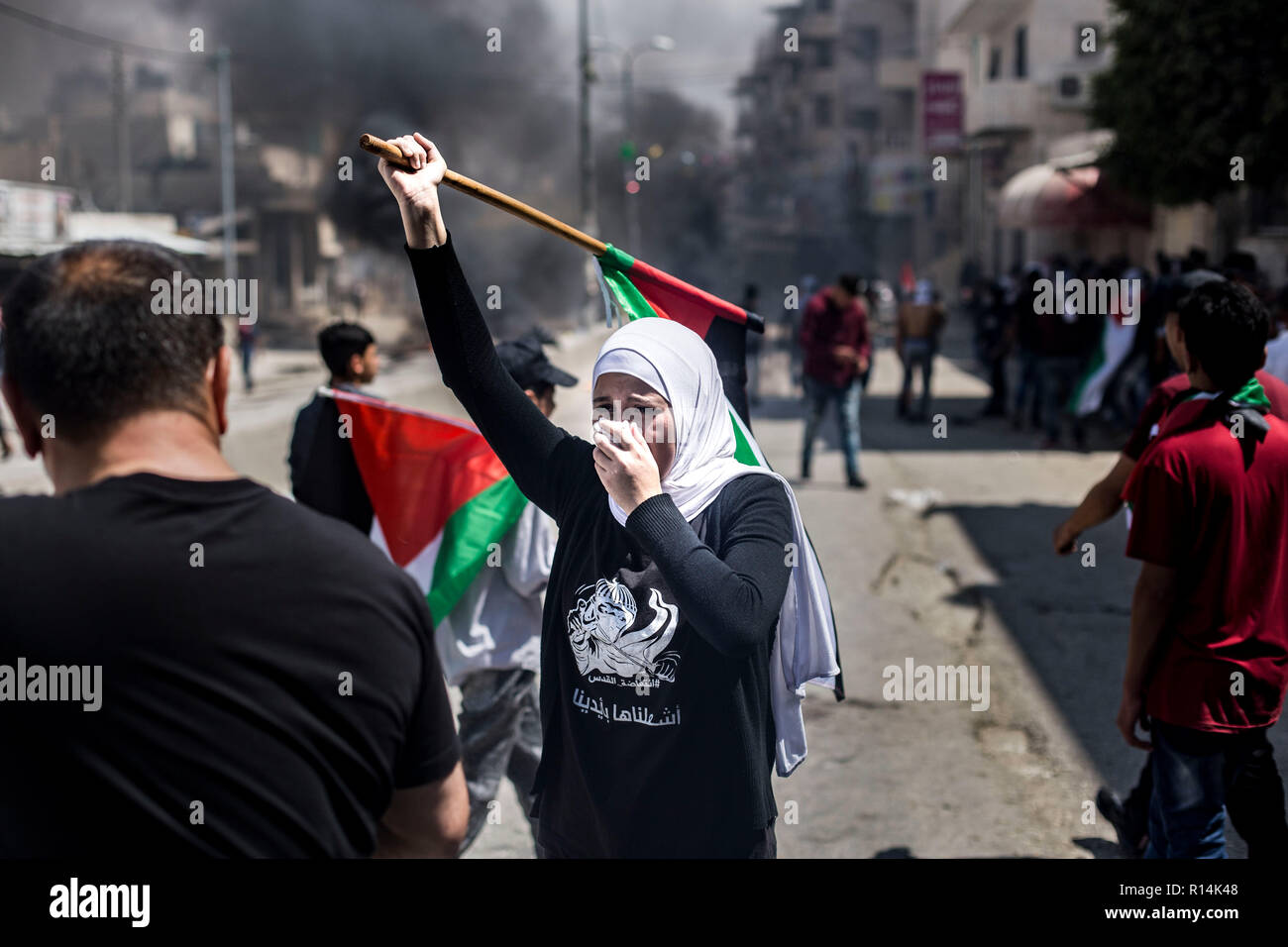 Une femme vu couvrant son visage tout en tenant un drapeau palestinien pendant la manifestation. Comme le gouvernement américain se déplace l'ambassade à Jérusalem, des milliers de Palestiniens manifestation à Gaza et la Cisjordanie le même jour qui marque le 70e anniversaire de la Nakba. À Gaza, les troupes israéliennes ont tué plus de 58 personnes et blessé 2 000 ce jour-là. Qalandiya au contrôle militaire des centaines ont marché et ont jeté des pierres sur des soldats israéliens, qui ont riposté avec des tirs de balles réelles, balle en caoutchouc et des gaz lacrymogènes. Banque D'Images