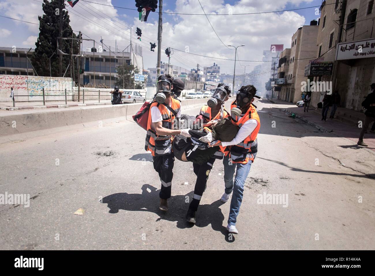 Vu une femme d'être prises pour l'ambulance par les ambulanciers après avoir été blessé lors de la manifestation. Comme le gouvernement américain se déplace l'ambassade à Jérusalem, des milliers de Palestiniens manifestation à Gaza et la Cisjordanie le même jour qui marque le 70e anniversaire de la Nakba. À Gaza, les troupes israéliennes ont tué plus de 58 personnes et blessé 2 000 ce jour-là. Qalandiya au contrôle militaire des centaines ont marché et ont jeté des pierres sur des soldats israéliens, qui ont riposté avec des tirs de balles réelles, balle en caoutchouc et des gaz lacrymogènes. Banque D'Images