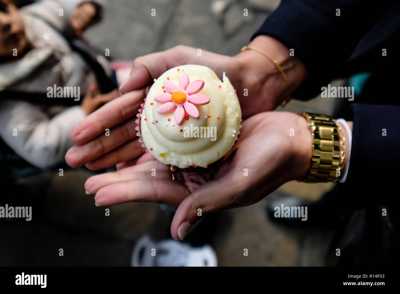 Woman holding cupcake blanc et rose dans ses mains, l'enfant en arrière-plan Banque D'Images