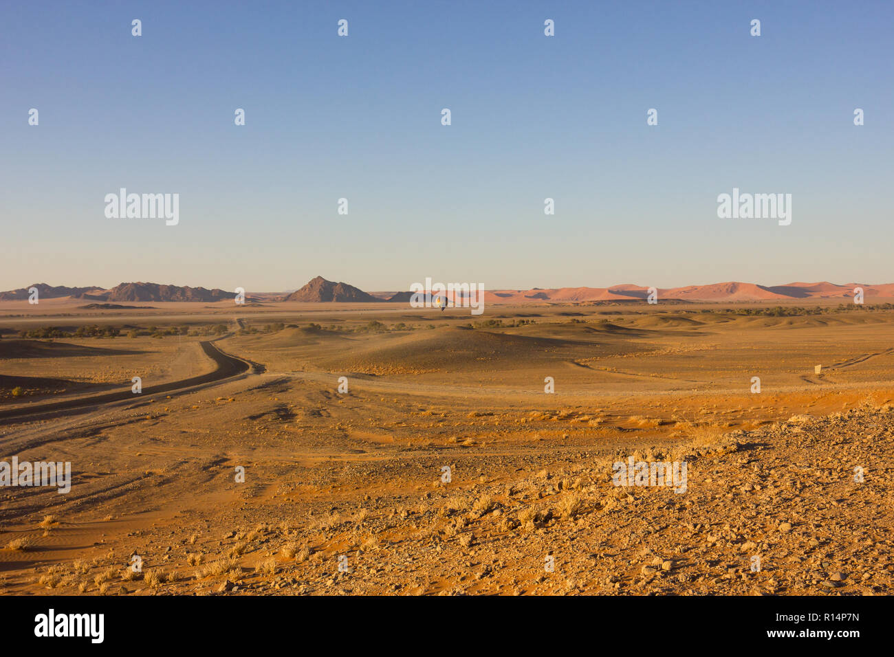 Vue paysage sur l'entrée de Sossusvlei et le Namib Naukluft national park avec un ballon à air chaud à l'atterrissage et une route goudronnée dans les dunes de sable Banque D'Images