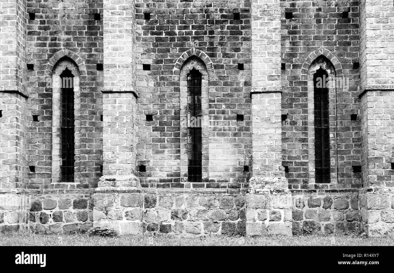 Détail de l'ancienne cathédrale monastère médiéval en pierre avec mur de brique et allongée windows en brique de style caractéristique de l'architecture gothique. Photo en bla Banque D'Images